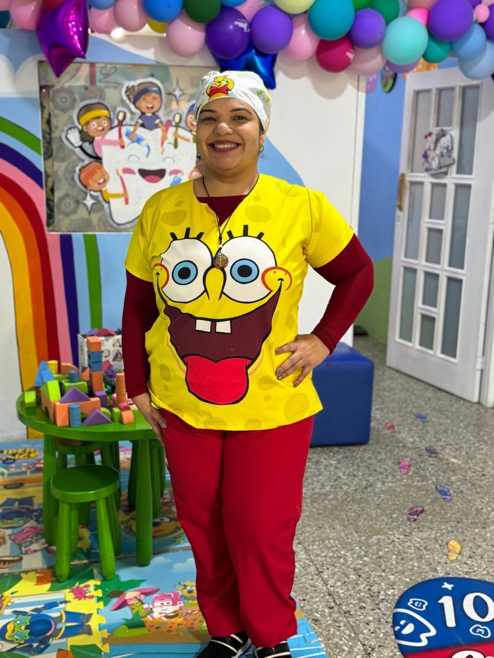 La Dra. Mine sonriendo con uniforme amarillo divertido en la sala de juegos del consultorio